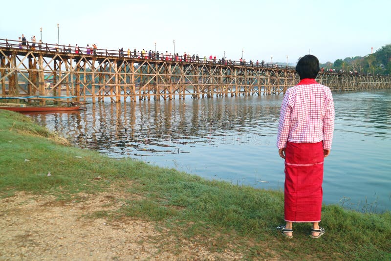 Hombre vestido de lomo tradicional mirando el icónico puente mon en Sangkhlaburi, Tailandia fotografía de archivo Hombre vestido de lomo tradicional mirando el icónico puente mon en Sangkhlaburi, Tailandia fotografía de archivo