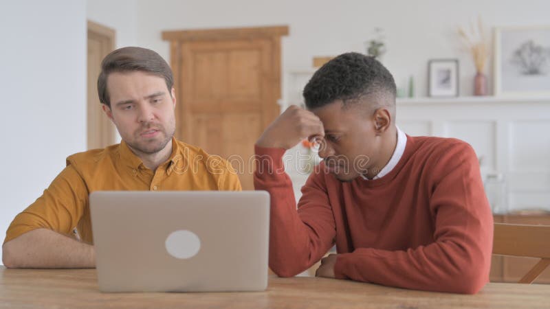 Hombre y joven africano reaccionando a la pérdida en laptop fotografía de archivo libre de regalías