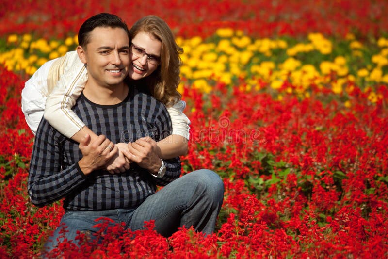 Hombre y mujer en corchetes que ríen en las flores fotografía de archivo Hombre y mujer en corchetes que ríen en las flores fotografía de archivo