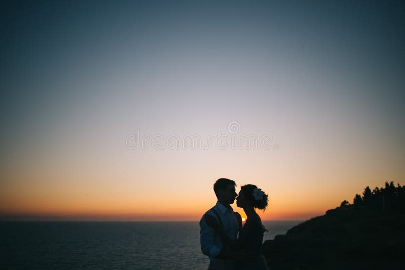 Hombre y mujer hermosos de los pares en la puesta del sol en el mar imagen de archivo libre de regalías Hombre y mujer hermosos de los pares en la puesta del sol en el mar imagen de archivo libre de regalías
