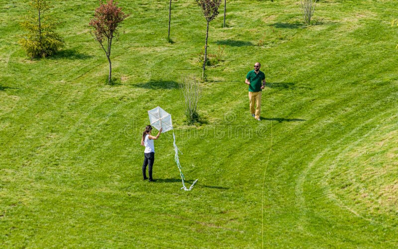 Hombre y mujer que vuelan una cometa blanca en un parque fotos de archivo Hombre y mujer que vuelan una cometa blanca en un parque fotos de archivo