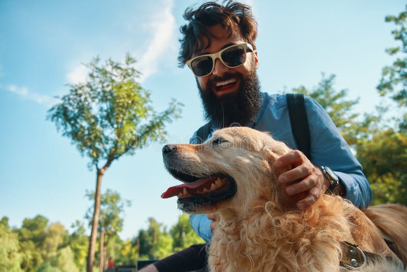 Hombre y perro que se divierten, el jugar, haciendo caras divertidas mientras que restin imagen de archivo Hombre y perro que se divierten, el jugar, haciendo caras divertidas mientras que restin imagen de archivo