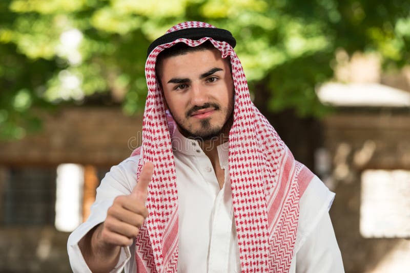 Hombre árabe de los emiratos del saudí que detiene los pulgares fotos de archivo libres de regalías