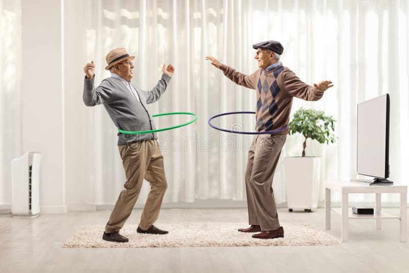 Hombres ancianos divertidos girando bucles de hula en una habitación