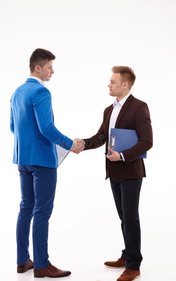 Hombres de negocios jovenes hermosos que sacuden las manos, colocándose foto de archivo libre de regalías Hombres de negocios jovenes hermosos que sacuden las manos, colocándose foto de archivo libre de regalías