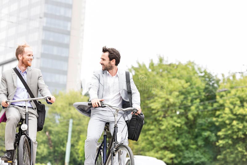 Hombres de negocios que hablan mientras que el montar monta en bicicleta al aire libre fotografía de archivo Hombres de negocios que hablan mientras que el montar monta en bicicleta al aire libre fotografía de archivo