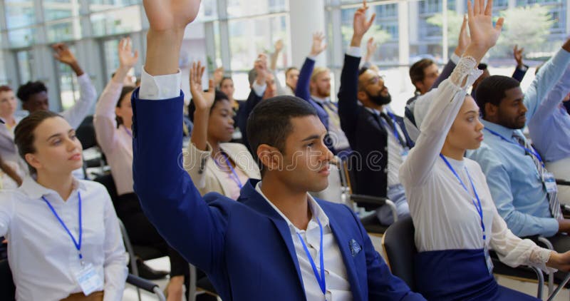 Hombres de negocios étnicos multi que aumentan las manos en el seminario 4k del negocio