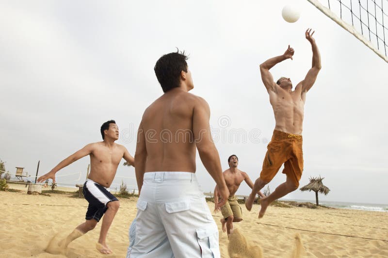 Hombres jovenes que juegan a voleibol en la playa imagen de archivo Hombres jovenes que juegan a voleibol en la playa imagen de archivo
