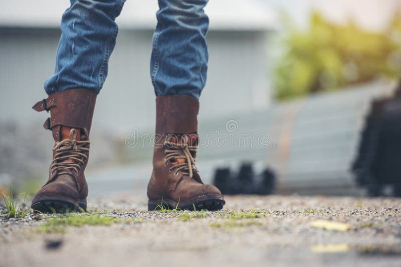Hombres Usan Botas De Construcción Zapatos De Seguridad Para Trabajadores En El Sitio De Construcción. Ingeniero Usar Jeans Botas Foto de archivo - Imagen de manera: 230703144