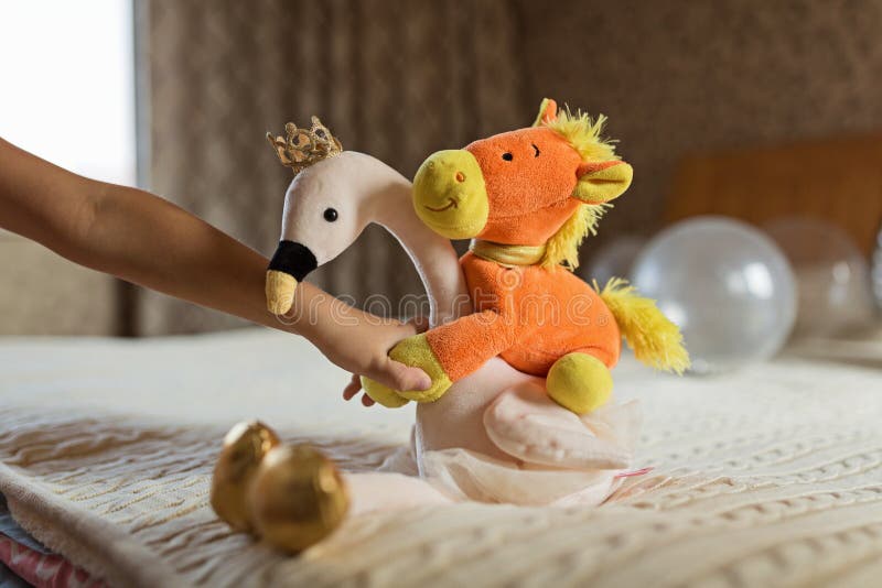 Home bedroom interior. Kid hand holding stuffed flamingo and horse toys in bedroom stock image Home bedroom interior. Kid hand holding stuffed flamingo and horse toys in bedroom stock image