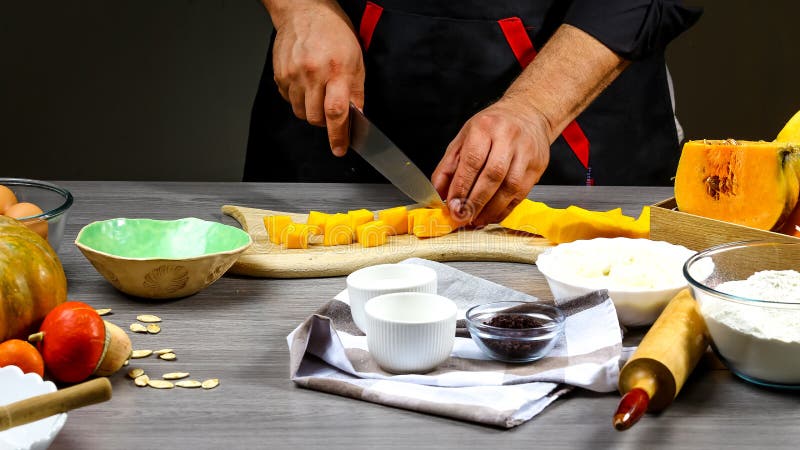 Home cooking American pumpkin pie with cheese and cooking ingredients with a cutting board on the background of a wooden table,The stock image Home cooking American pumpkin pie with cheese and cooking ingredients with a cutting board on the background of a wooden table,The stock image