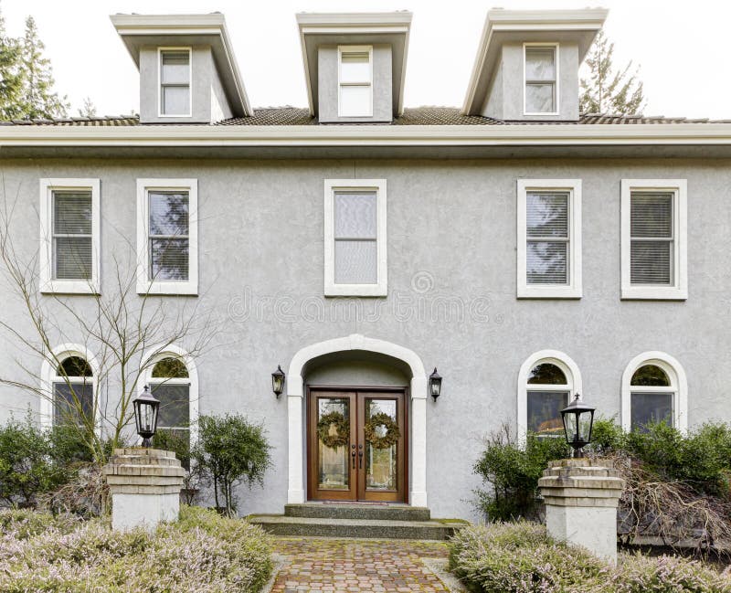 Home exterior of large grey classic house with many narrow windows.