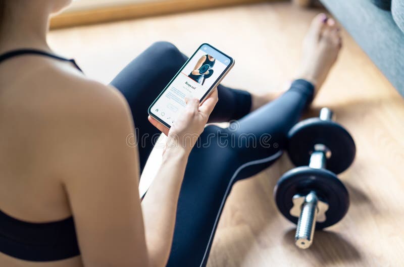 Home gym workout with online exercise app in phone. Fit woman watching training tutorial video or using digital personal trainer. Home gym workout with online