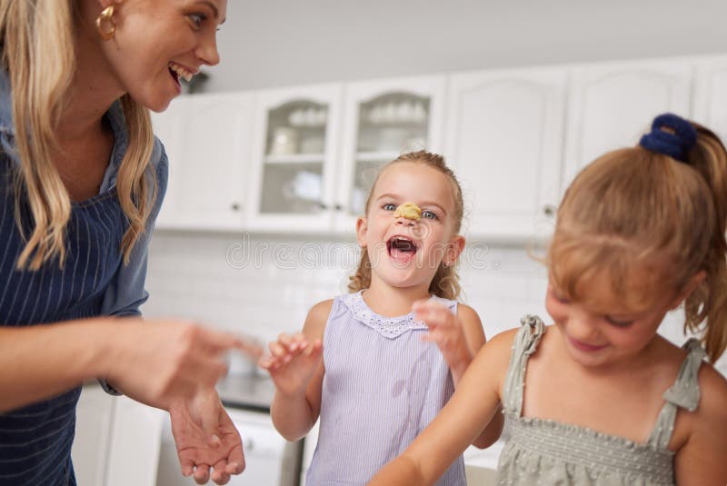 Home kitchen, children play while cooking with happy mother and funny family time learning to bake. Crazy girl child royalty free stock image