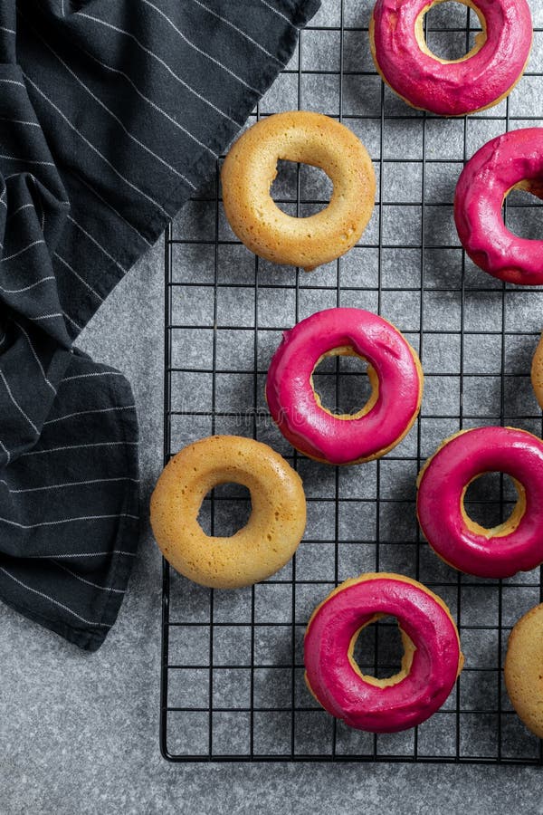 Home Made Baking Fresh Baked Donuts with Bright Pink Icing on Cooling