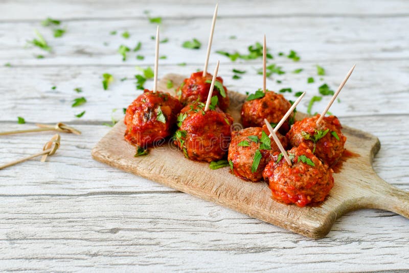 Meat balls with tomato sauce and fresh parsley on cutting board