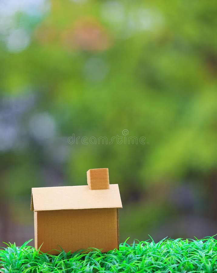 Home making from old recycle paper box lying on green grass field with beautiful blur background use for home house residence topic