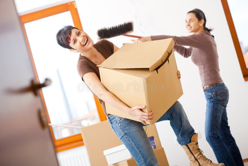 Young women lifting up cardboard box and having fun, while moving to new home. Young women lifting up cardboard box and having fun, while moving to new home.