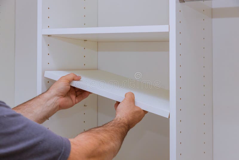 Worker sets the shelf for closet cabinet