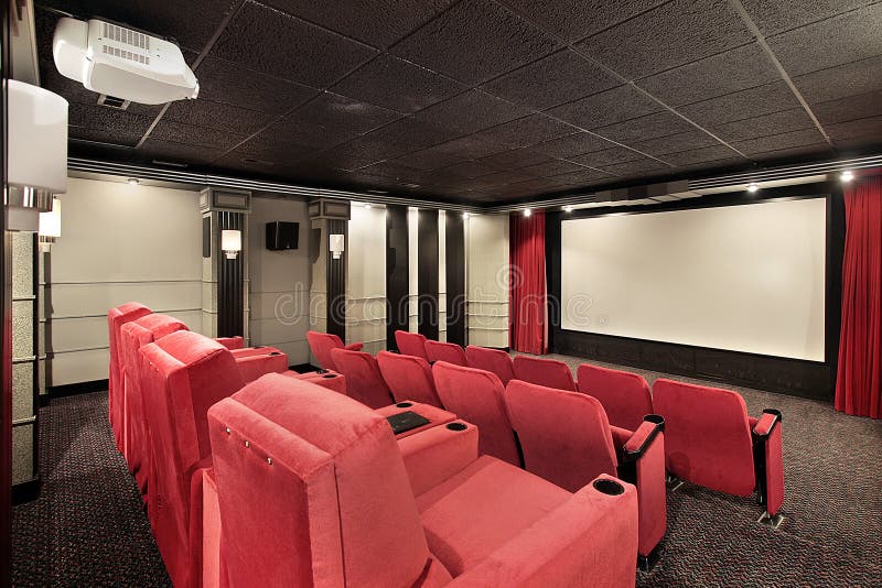 Domácí kino v luxusním domě s červenými židlemi.