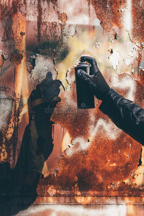 Homeless man spray painting old train wagon with aerosol can. Unrecognizable male person hand close up in conceptual image with selective focus