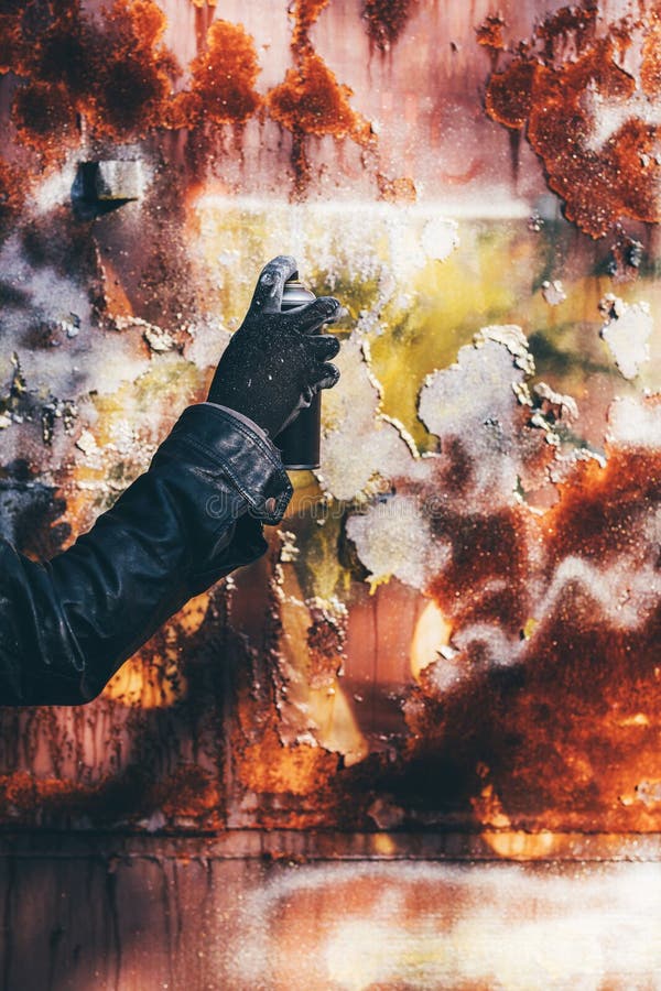 Homeless man spray painting old train wagon with aerosol can. Unrecognizable male person hand close up in conceptual image with selective focus