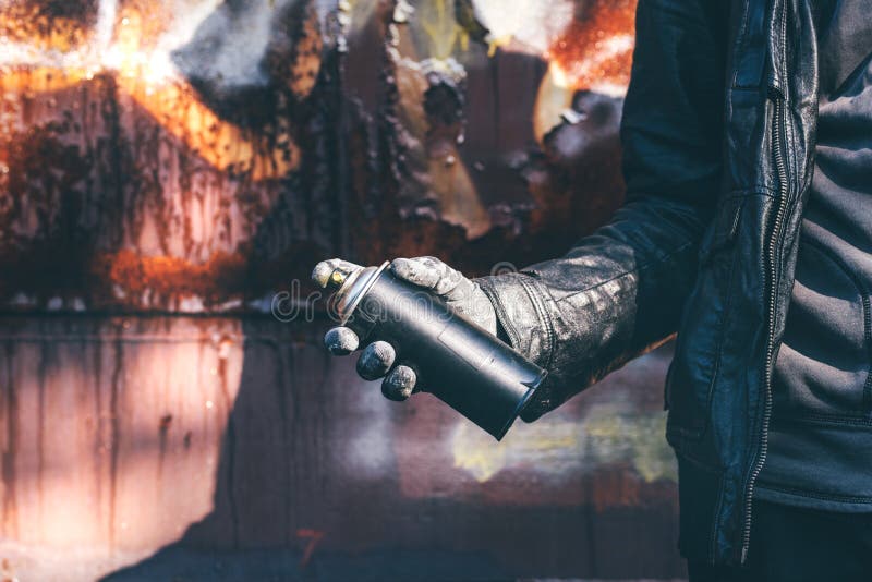 Homeless man spray painting old train wagon with aerosol can. Unrecognizable male person hand close up in conceptual image with selective focus