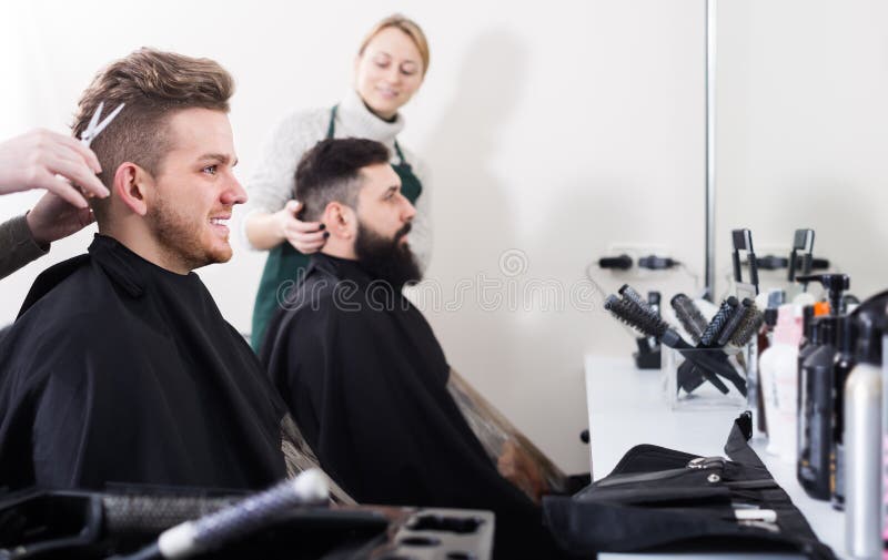 Homem adulto que tem seu cabelo cortado por cabeleireiro
