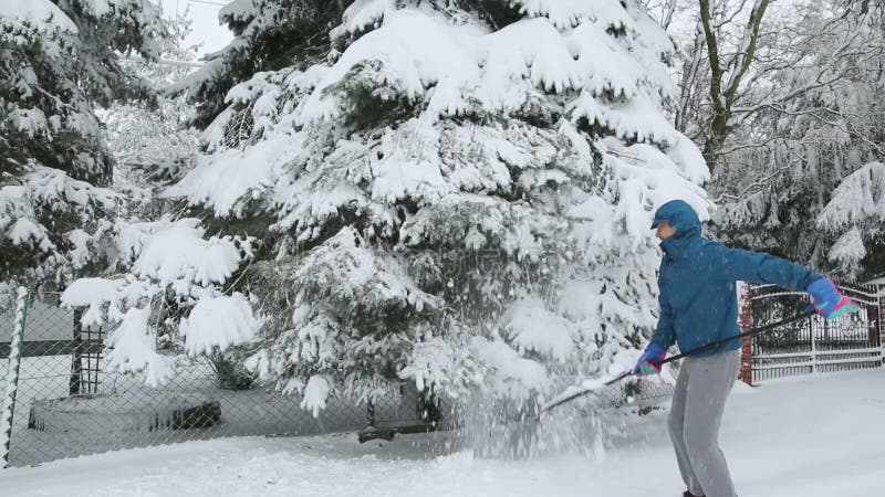 Homem adulto retirando neve de árvores no jardim