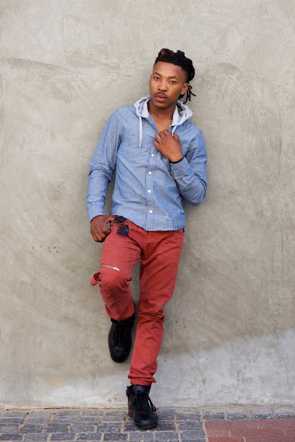 Homem africano fresco do comprimento completo com os dreadlocks que inclinam-se contra a parede imagens de stock royalty free Homem africano fresco do comprimento completo com os dreadlocks que inclinam-se contra a parede imagens de stock royalty free