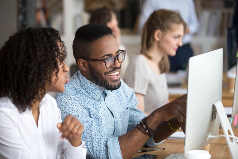 Homem afro-americano de sorriso que mostra a notícia engraçada ao colega foto de stock Homem afro-americano de sorriso que mostra a notícia engraçada ao colega foto de stock