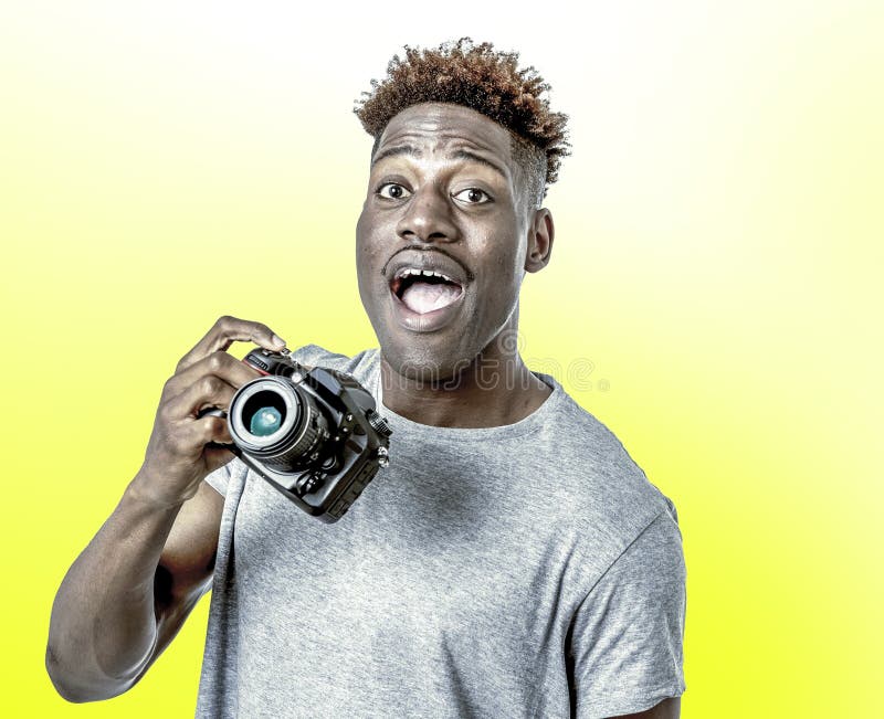 Homem afro-americano preto feliz atrativo e fresco novo que mantém o sorriso reflexo digital da câmera da foto entusiasmado no CC imagem de stock Homem afro-americano preto feliz atrativo e fresco novo que mantém o sorriso reflexo digital da câmera da foto entusiasmado no CC imagem de stock