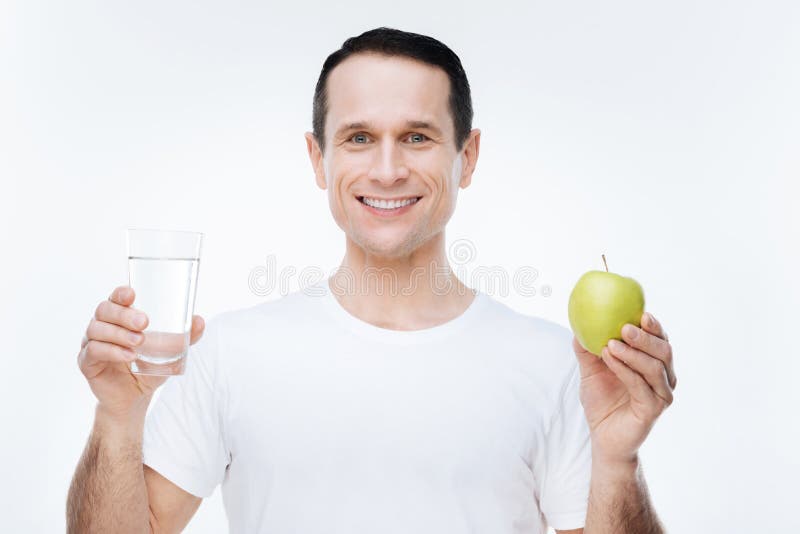 Homem agradável alegre que guarda uma maçã imagem de stock royalty free Homem agradável alegre que guarda uma maçã imagem de stock royalty free