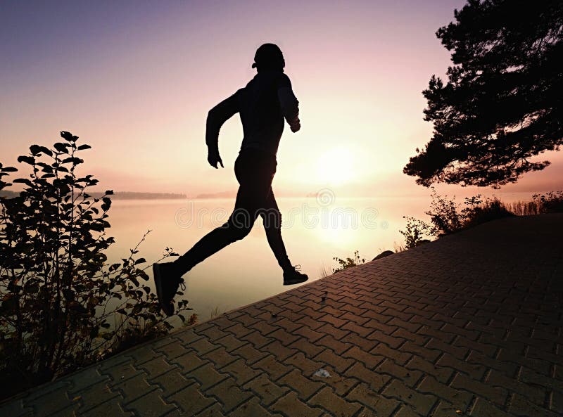 Homem alto com óculos de sol, o boné de beisebol vermelho e a corrida do sportswear imagem de stock Homem alto com óculos de sol, o boné de beisebol vermelho e a corrida do sportswear imagem de stock