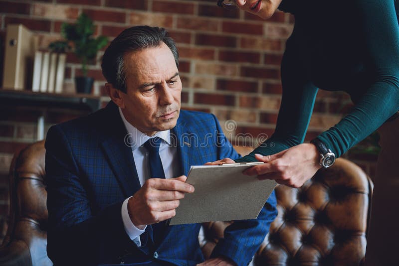 Homem amadurecido sério que olha a tabuleta fotografia de stock Homem amadurecido sério que olha a tabuleta fotografia de stock