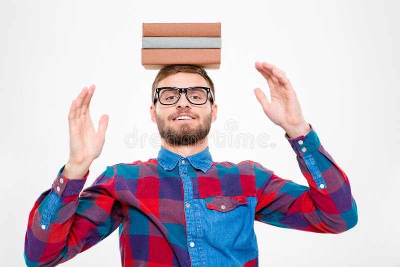 Homem amusing feliz nos vidros com os livros em sua cabeça imagem de stock royalty free Homem amusing feliz nos vidros com os livros em sua cabeça imagem de stock royalty free