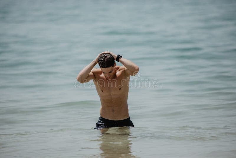 Homem apto do caucasian 'sexy' que levanta em uma praia na água