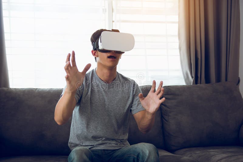 Homem asi?tico novo que veste vidros da realidade virtual na sala de visitas para admirar a realidade virtual fotos de stock Homem asi?tico novo que veste vidros da realidade virtual na sala de visitas para admirar a realidade virtual fotos de stock