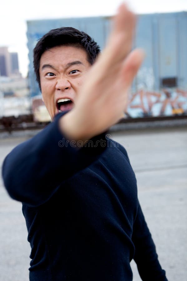 An angry asian man performing karate moves toward the camera. An angry asian man performing karate moves toward the camera