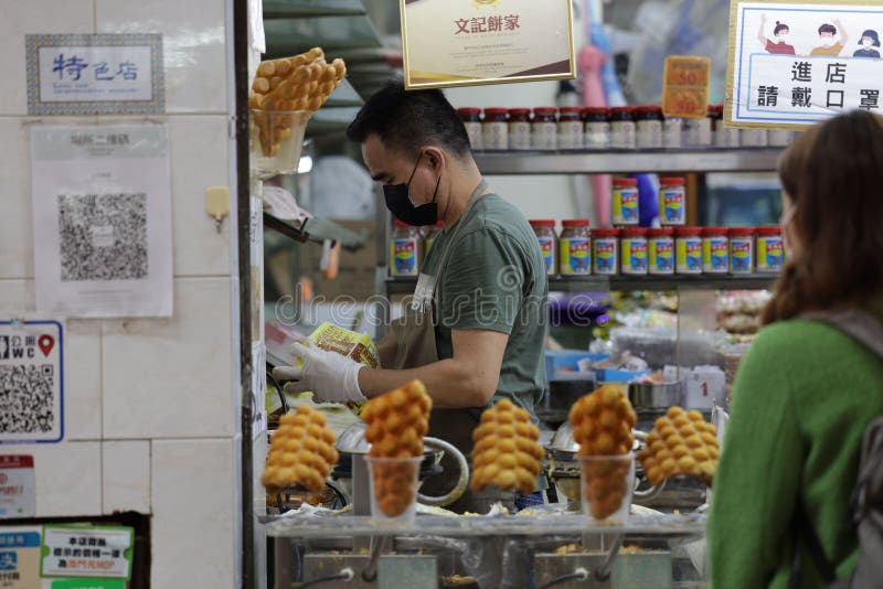 Homem atrás de um balcão preparando waffles frescos numa rua movimentada na china fotografia de stock royalty free