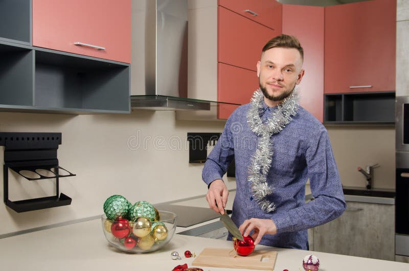 Homem barbudo atrativo com uma pitada festiva no pescoço está preparando um jantar festivo de Ano Novo Um homem está preparando u foto de stock royalty free Homem barbudo atrativo com uma pitada festiva no pescoço está preparando um jantar festivo de Ano Novo Um homem está preparando u foto de stock royalty free