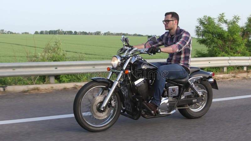 Homem brutal que monta uma motocicleta Tiro aéreo