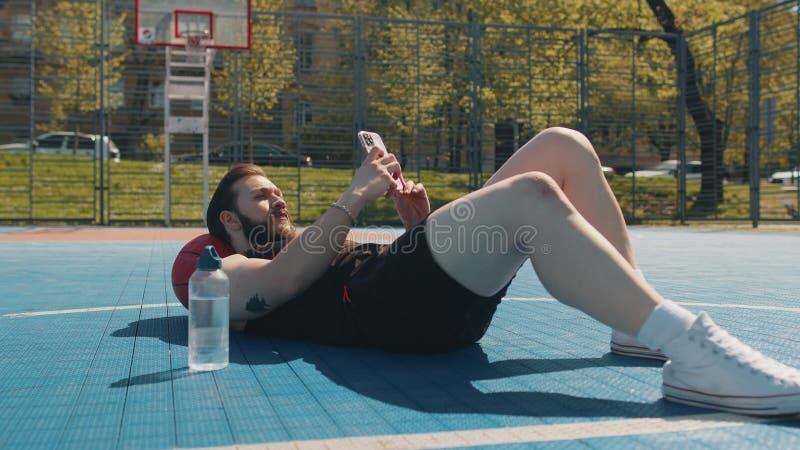 Um Homem Relaxando Depois Do Treino De Basquetebol E Pesquisando