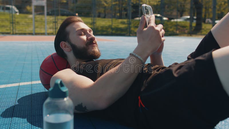 Um Homem Relaxando Depois Do Treino De Basquetebol E Pesquisando