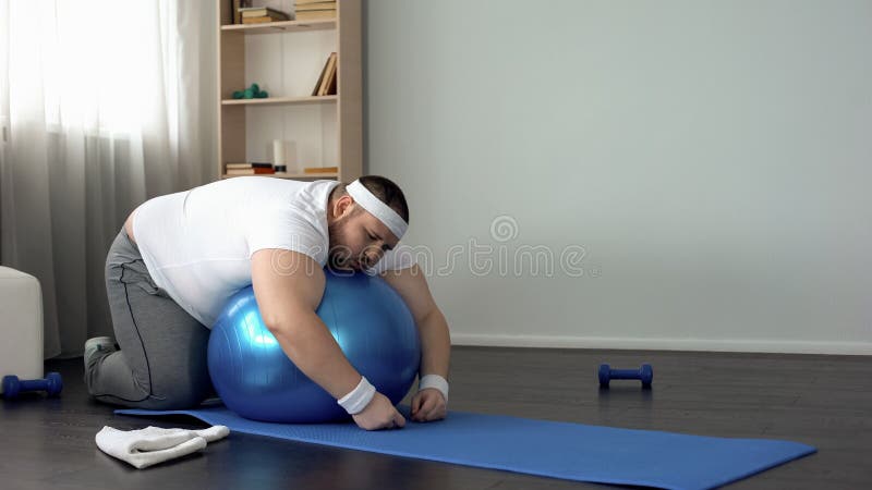 Homem carnudo que descansa após o exercício, encontrando-se na bola da aptidão, desejo perder o peso fotos de stock royalty free Homem carnudo que descansa após o exercício, encontrando-se na bola da aptidão, desejo perder o peso fotos de stock royalty free