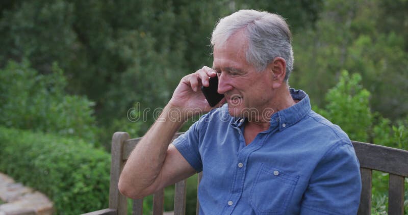 Homem caucasiano sênior sorrindo e falando ao telefone no jardim