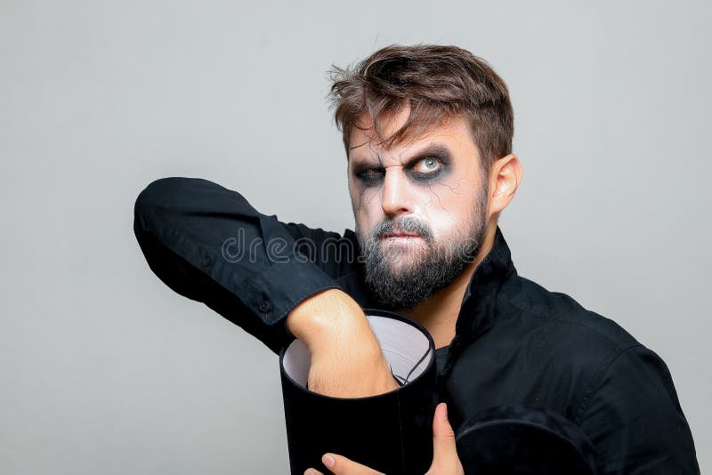 Um homem com barba e maquiagem de morto-vivo no halloween mantém as mãos na  frente dele