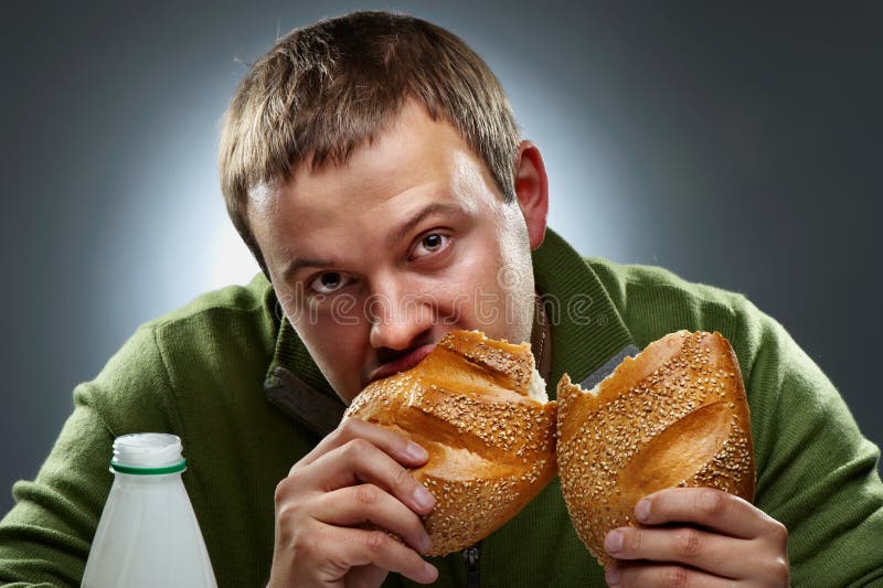 Homem com fome com a boca cheia do pão foto de stock royalty free Homem com fome com a boca cheia do pão foto de stock royalty free