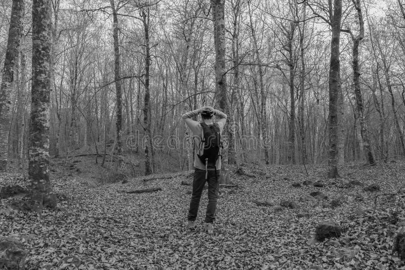 Homem com mochila e mãos na cabeça caminhando na floresta perdido em perigo de natureza concepção solitária e estilo de vida depre