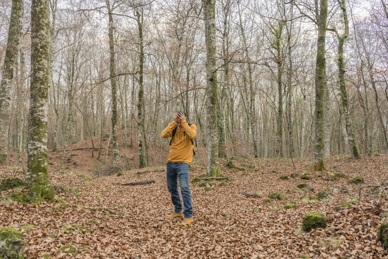 Homem com mochila e mãos na cabeça caminhando na floresta perdido em perigo de natureza concepção solitária e estilo de vida depre